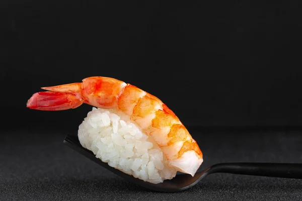 特写镜头的黑鬼寿司，黑色背景的黑色叉子上有鲜虾 — 图库照片