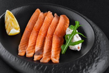 Taze tuzlanmış somon, limon ve peynirli tabakta.