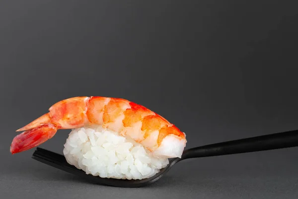 特写镜头的黑鬼寿司，黑色背景的黑色叉子上有鲜虾 — 图库照片