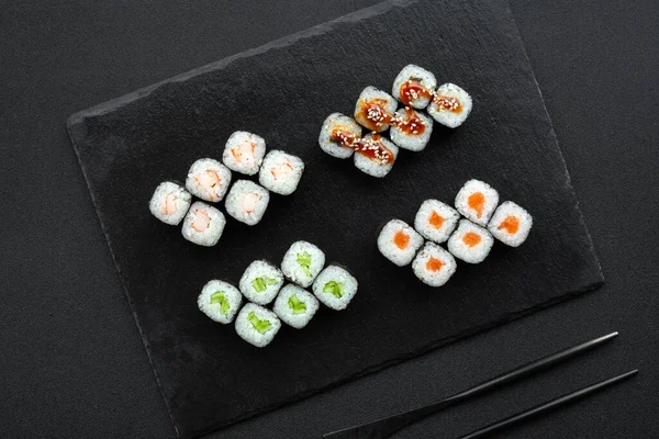 Portie klassieke verse sushi broodjes met nori, zalm, komkommer, gerookte paling — Stockfoto