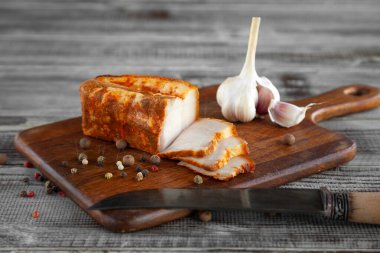 Tütsülenmiş ya da tuzlanmış domuz yağı, biber, ahşap kesim tahtasındaki sarımsak.