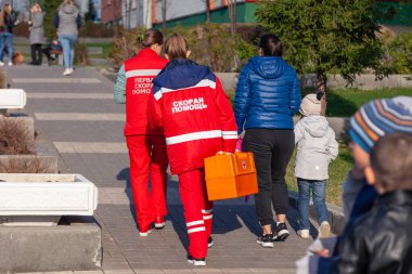 Rusya Kemerovo 2019-05-21 ambulansı kırmızı üniformalı ve turuncu ilaç çantalı bir kadın sonbaharda parkta yürüyor. Arka plan