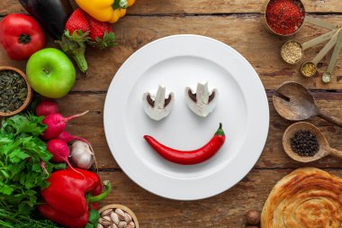 Çeşitli sebzelerin, otların, doğuya özgü baharatların, beyaz tabağın üst görüntüsü.