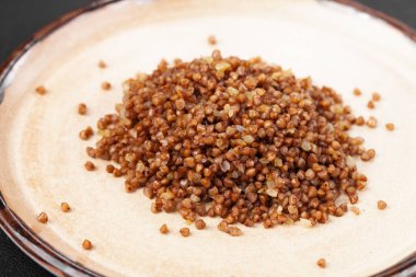 Gri tabakta yan yemeğin porsiyonu - haşlanmış karabuğday lapası.