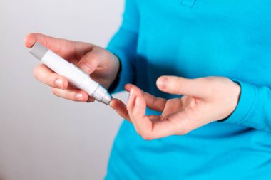 Beyaz arka plan üzerinde kan glukoz monitör kullanan diyabetik kız görünümünü midsection