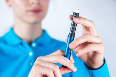 İnsülin Kalem beyaz arka planda tutan kadın eli