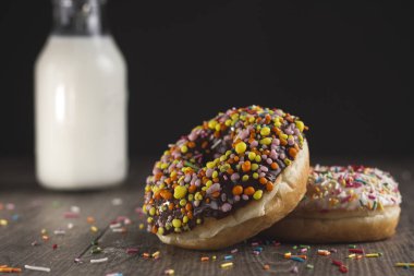 Ahşap masanın üzerinde yatan iki çörek. Çörek ahşap bir masa üzerinde bir şişe süt yanındadır