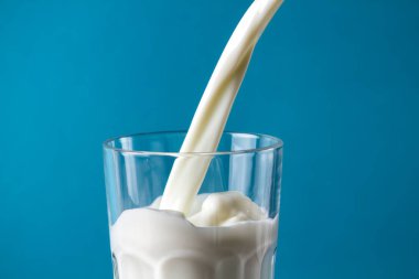 Mavi bir arka plan üzerine bir bardak sütte sıçramasına