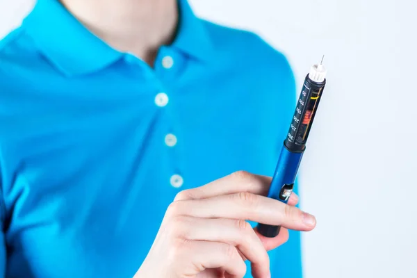 Hand of woman holding insulin pen on white background