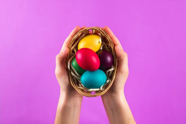 Colorful Easter eggs in hands against the colorful background