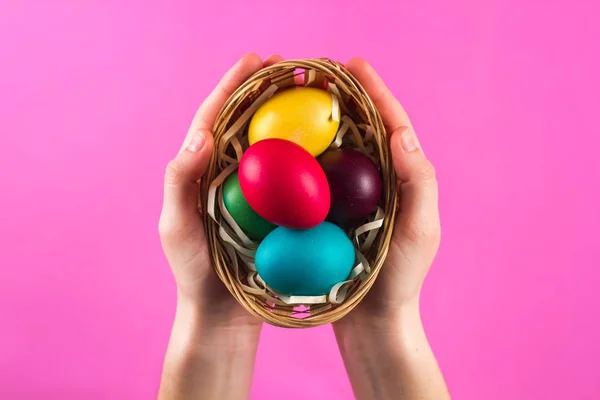 Colorful Easter eggs in hands against the colorful background