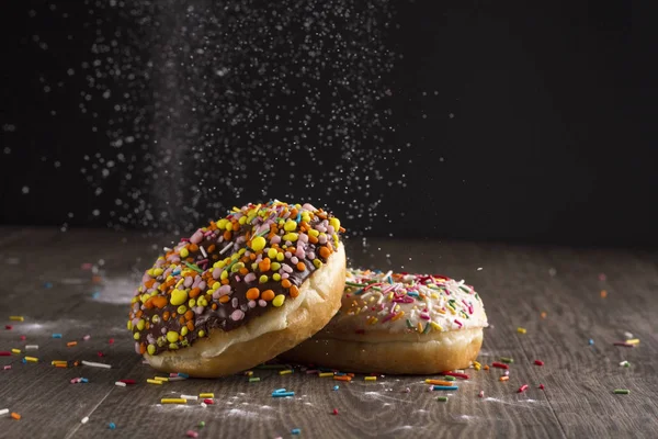 İki donut masada ve siyah bir zemin üzerine yalan.