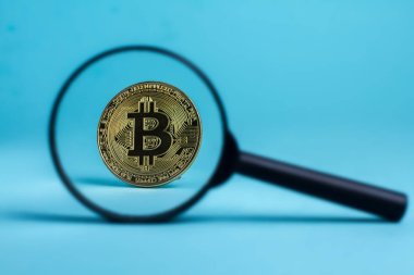 Büyüteç cam altın bitcoin sikke üzerinde mavi arka plan ile 