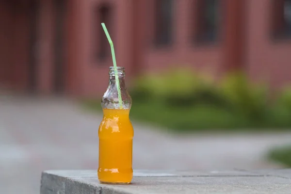 close up of beverage in bottle with green straw