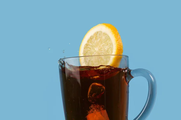 Свіжий Соковитий Жовтий Лимон Падає Чашку Чорного Чаю Синьому Фоні — стокове фото