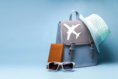 Картина, постер, плакат, фотообои "женский туристический рюкзак хипстера с паспортом и шляпой на синем фоне
", артикул 211766336