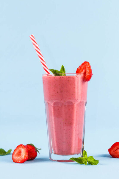 glass of strawberry smoothie with mint on blue background