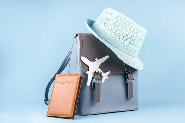 Женский туристический рюкзак хипстера с паспортом и шляпой на синем фоне
