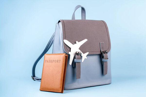 Женский туристический рюкзак хипстера с паспортом и шляпой на синем фоне
