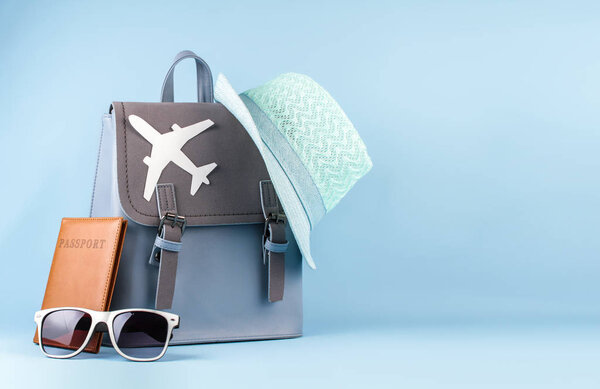 Женский туристический рюкзак хипстера с паспортом и шляпой на синем фоне
