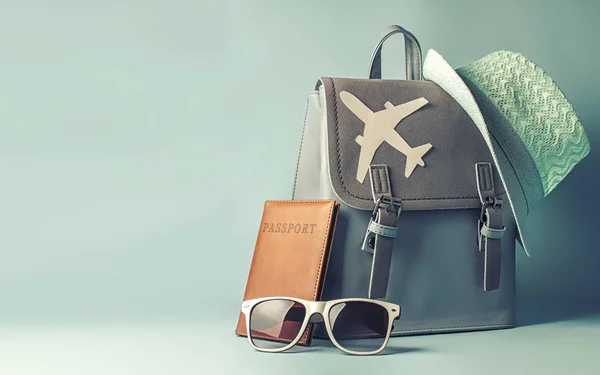 Female hipster tourist backpack with passport and hat on blue background