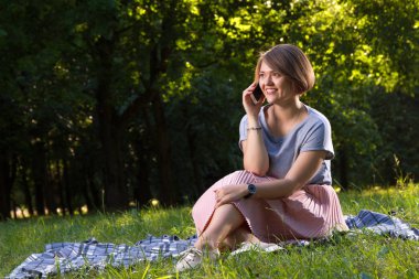 Sonbahar parkta Smartphone kullanarak gülümseyen genç kadın 