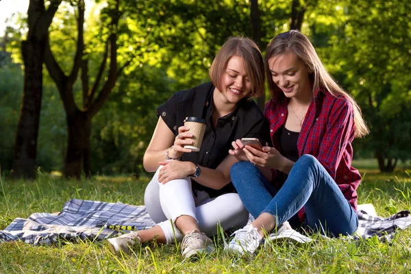 Parkta oturan ve smartphone kullanarak iki genç kız