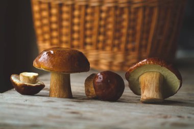 Hasır sepet arka plan üzerinde ahşap masa üzerinde üç orman mantar