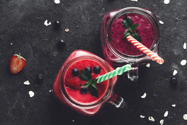 Top view of smoothies from raspberries and blueberries in glass jars.