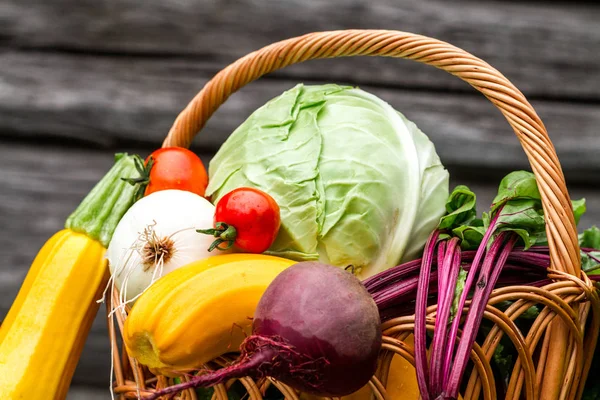 Food composition of fresh vegetables in basket on wooden background. Healthy food concept.