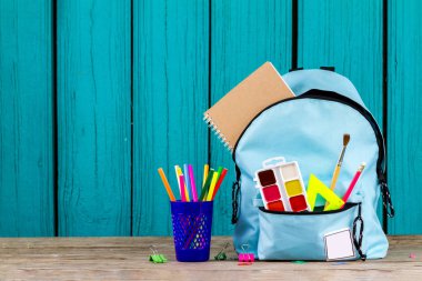 School backpack with stationery on blue, wooden background. Back to school. Copy space. clipart