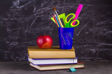 Kitap, apple ve okul malzemeleri eski püskü siyah arka plan üzerine.