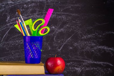 Kitap, apple ve okul malzemeleri eski püskü siyah arka plan üzerine.