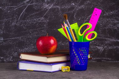 Kitap, apple ve okul malzemeleri eski püskü siyah arka plan üzerine.