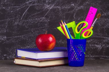 Kitap, apple ve okul malzemeleri eski püskü siyah arka plan üzerine.