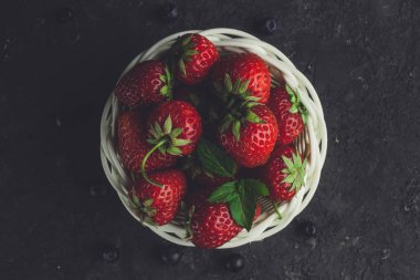 Siyah arka plan üzerine beyaz sepet içinde taze çilek.