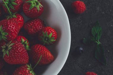 Koyu arka plan üzerinde beyaz kase taze çilek