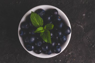 Yaban mersini ve nane üstten görünüm beyaz kase siyah arka plan üzerine bırakır.. 