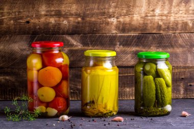 Kavanoz turşu kabak, salatalık ve domates ahşap arka plan üzerinde. Sonbahar kavramı. Gıda stoku