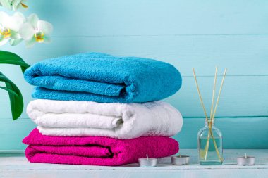 Havlu, bir dal orkide bir aroma, sopa ve mavi bir arka plan üzerinde bir mum. Spa. Hijyen. Aroma terapi