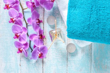 Havlu, orkide, mumlar ve aroma dalı ahşap, mavi zemin üzerine yapışır. Spa uygulamaları, hijyen, banyo, duş. Spa. Üstten görünüm