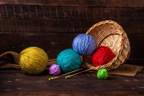 Bright, colored thread for knitting and knitting needles for knitting on a dark, wooden background. Knitting concept