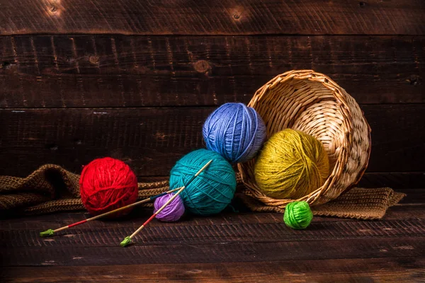 Bright, colored thread for knitting and knitting needles for knitting on a dark, wooden background. Knitting concept