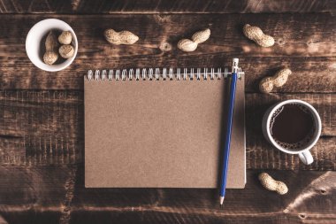 Düz yatıyordu. Çalışma alanı. Kahve, cep telefonu, fıstık ve defter. Evde çalışıyorum. Üstten görünüm. Kopya alanı