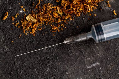 Tütün ve şırınga siyah bir arka plan. Nikotin bağımlılığı tedavisinde. Hayatı için tehlike. Sigara durdurmak