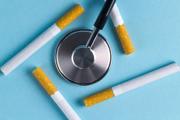Nicotine, tobacco addiction. Harmful, unhealthy habit. Cigarette and stethoscope on a blue background. Medical assistance to dependent people. Concept stop smoking