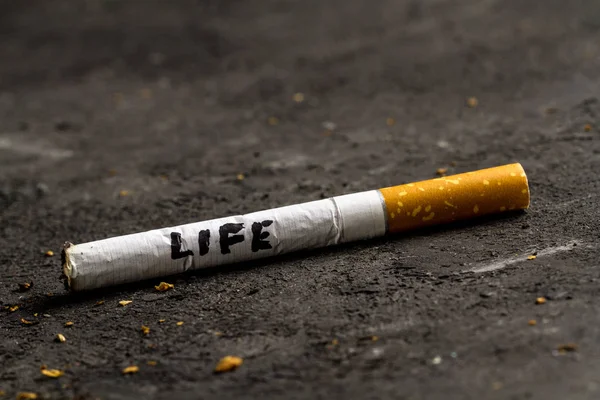 Nicotine, tobacco addiction. Harmful, unhealthy habit. A cigarette lies on a black background. Smoking concept