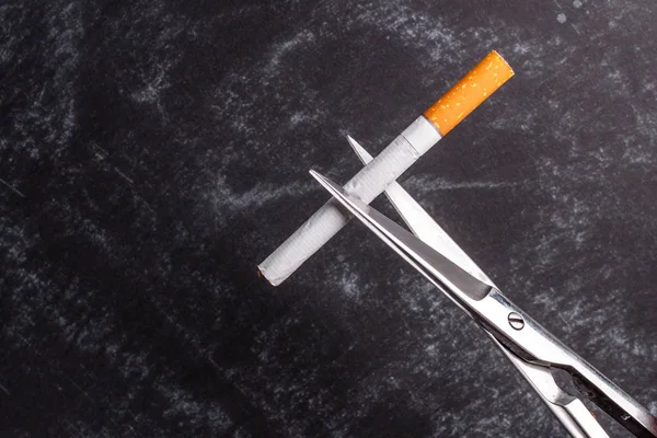 The concept of the fight against smoking. Nicotine addiction. Scissors cuts a cigarette