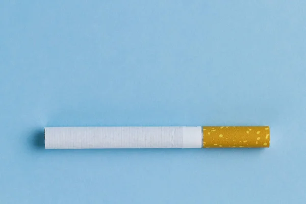 Nicotine, tobacco addiction. Harmful, unhealthy habit. A cigarette lies on a blue background. Smoking concept