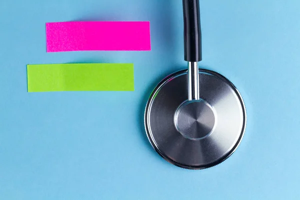 Stethoscope and stickers for notes on a blue background. Top view. Copy space